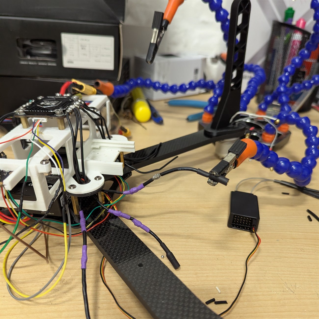 The drone mid-rebuild on a workbench with helping hands, custom heat-shrunk cables and a 4-in-1 ESC